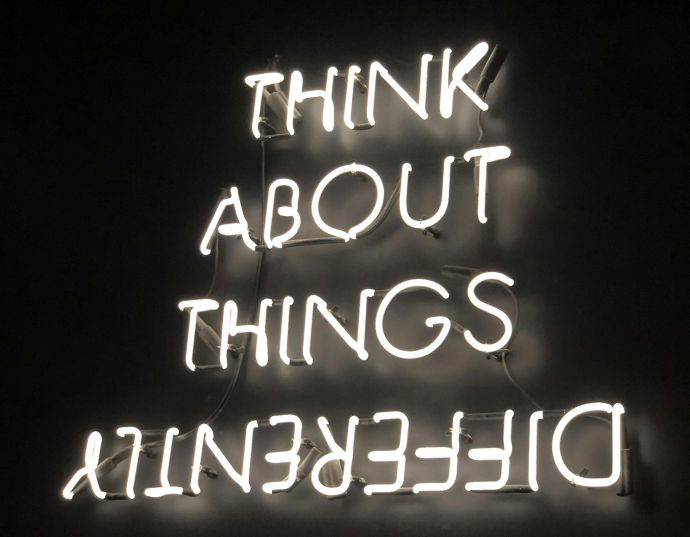 A glowing neon sign displaying an upside-down motivational quote against a dark background.